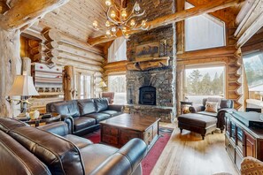 Ein Holzblockhaus-Interieur mit Kamin aus Stein, Ledermöbeln und einer Kristallleuchtre.