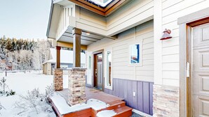 A two-story house with a covered porch, a stone pillar, and a wooden front door. - Modern McCall Family Retreat, Loft, AC, Deck (McCall)