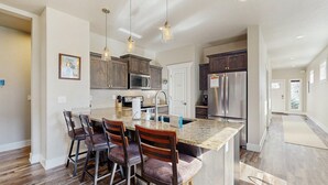 A spacious kitchen with a central island, bar stools, stainless steel appliances, and pendant lighting. - Modern McCall Family Retreat, Loft, AC, Deck (McCall)