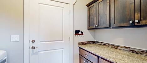 A kitchen with a white door, dark wooden cabinets, and a granite countertop.
