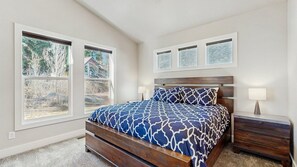 Ein Schlafzimmer mit einem Bett, zwei Nachttischen, einem Fenster und einem Wandbild.