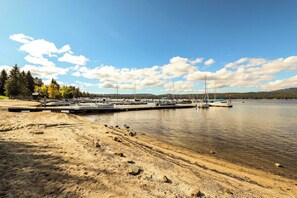 A lakeside dock with boats, a sandy beach, and trees in the background. - Golf Course Condo | Pools, Hot Tub & Fitness (McCall)