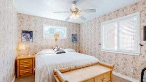 Een slaapkamer met een bed, een houten nachtkastje, een lamp en een raam met zonwering.