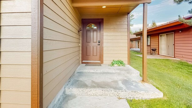 Una casa de madera con una puerta marrón, un porche de concreto y el número 143 en la pared.