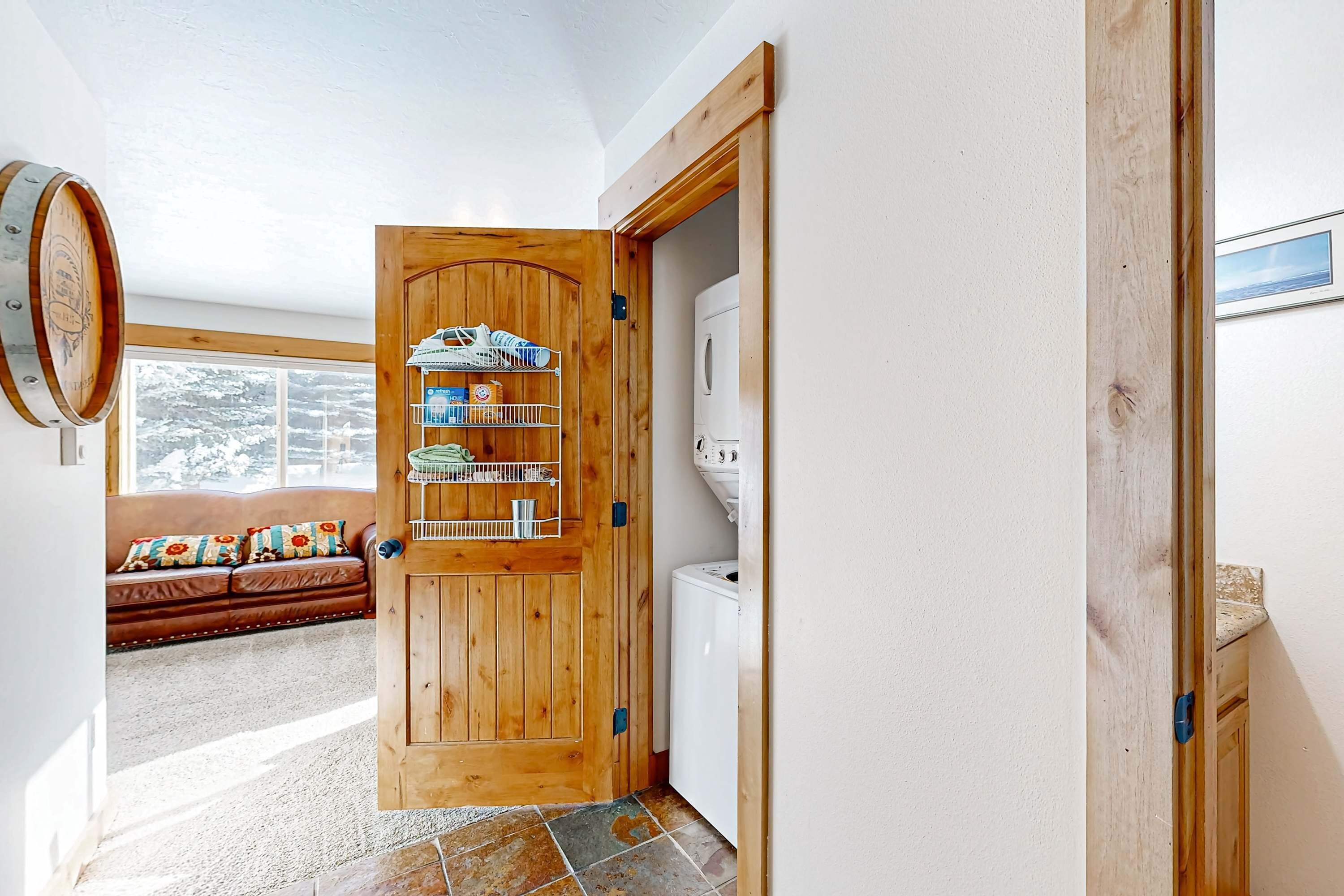 A wooden door leading to a kitchen with a built-in shelf and a white refrigerator.