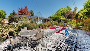 Une terrasse avec un sol à motifs, du mobilier d’extérieur et une balançoire.