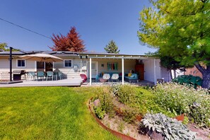 Une maison dotée d’un patio couvert, d’un espace salon extérieur et d’un jardin.