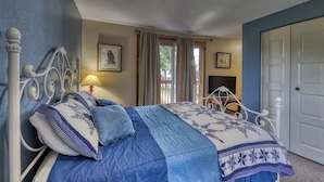 A bedroom with a bed, curtains, a door, and a window.