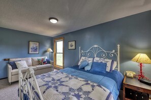 A bedroom with a bed, a nightstand, a lamp, a window, and a door. - Slope-Side Getaway Deck Pool Table Views (Boise)