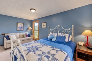 A bedroom with a bed, a sofa, a window, and a bedside table with a lamp. - Bogus Basin Ski-In/Ski-Out Condo, Two Decks (Boise)