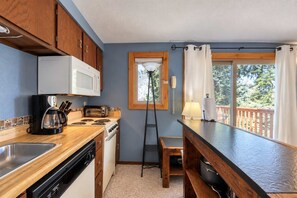 A compact kitchen with a microwave, toaster, coffee maker, and stove. A wooden counter and a sink are visible. - Bogus Basin Ski-In/Ski-Out Condo, Two Decks (Boise)