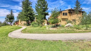A residential area with a paved driveway leading to a two-story house with a brown exterior.