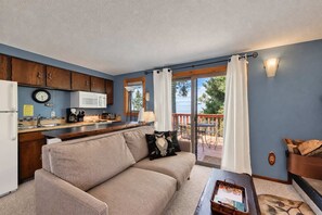 A cozy living room with a sofa, a coffee table, and a view of the outdoors through a sliding glass door.