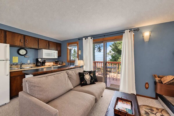 A cozy living room with a sofa, a coffee table, and a view of the outdoors through a sliding glass door. - Bogus Basin Ski-In/Ski-Out Condo, Two Decks (Boise)