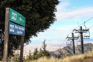 A signpost with directions to Buttercup and Bitter Root Basin, with a ski lift in the background.