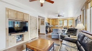 A spacious living area with a television, leather sofa, and a dining table. - Rustic-Modern Cabin with Hot Tub Access (McCall)