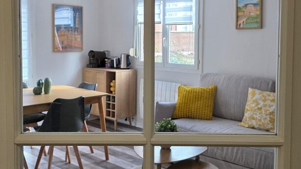 Ein Zimmer mit Essbereich, einer Couch und einem Fenster mit Blick auf Gebäude.