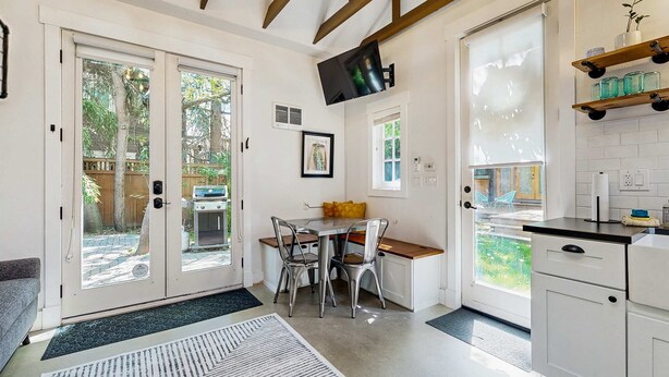 A modern kitchen with a dining area, large windows, and a TV mounted on the wall. - Charming Tiny Home in Boise's North End (Boise)