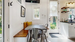 A modern kitchen with white cabinets, a wooden countertop, and a built-in oven. There is a window with a view of greenery outside. - Charming Tiny Home in Boise's North End (Boise)