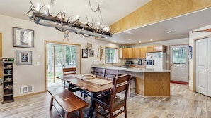 A modern kitchen with wooden cabinets, a central island, and a unique antler chandelier. - McCall Family Retreat Near Payette Lake | Hot Tub (McCall)