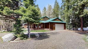 A lodge with a covered porch, a garage, and a gravel driveway surrounded by trees. - McCall Family Retreat Near Payette Lake | Hot Tub (McCall)