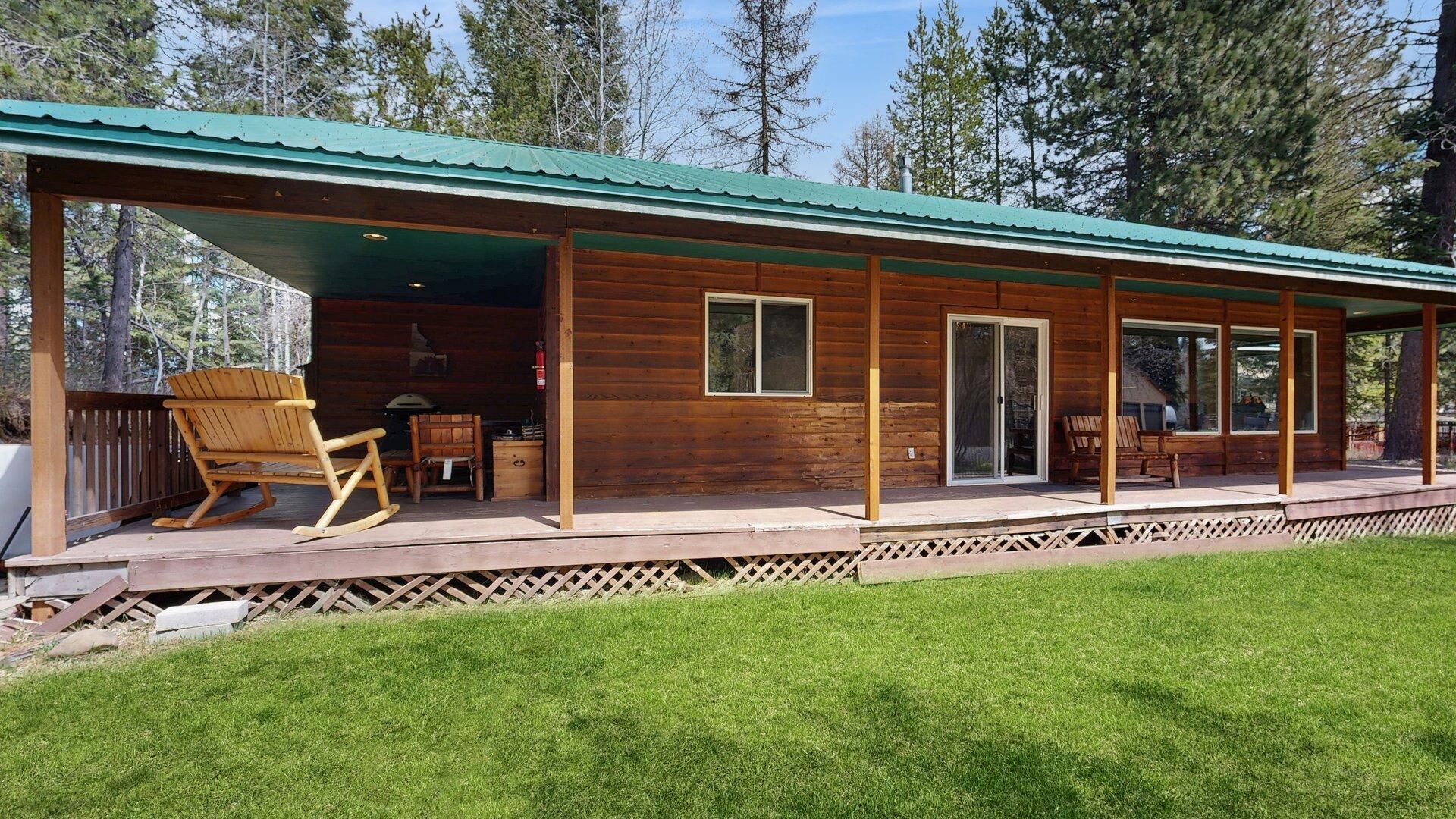 A wooden cabin with a covered porch, a grill, and a rocking chair.