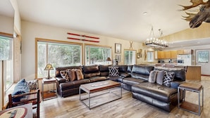 A spacious living room with a sectional sofa, a coffee table, and a chandelier. - McCall Family Retreat Near Payette Lake | Hot Tub (McCall)