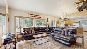 A spacious living room with a sectional sofa, a coffee table, and a chandelier. - McCall Family Retreat Near Payette Lake | Hot Tub (McCall)