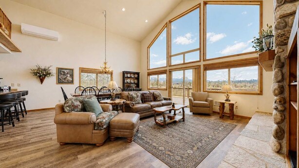 A spacious living room with a large window, a fireplace, and a stone accent wall.