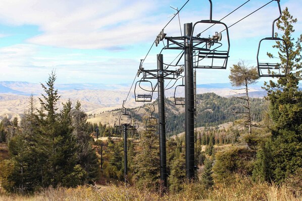 A mountain landscape with a ski lift and surrounding trees.