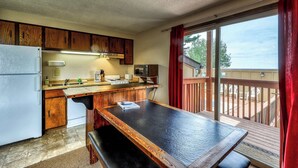A compact kitchen with wooden cabinets, a refrigerator, a sink, and a dining table. - Ski-In Ski-Out Bogus Basin Condo with 2 Decks (Boise)