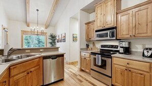 Una cucina moderna con mobili in legno, elettrodomestici in acciaio inossidabile e una finestra che si affaccia su alberi.