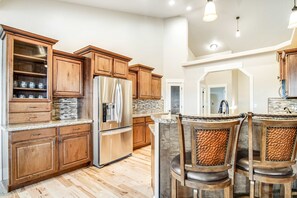 A kitchen with wooden cabinets, a stainless steel refrigerator, and a stone countertop. - Kerry Hill Manor, Vineyard Estate & Views (Wilder)
