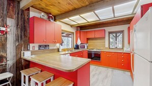 Una cocina compacta con armarios rojos, una encimera de madera y una estufa empotrada.