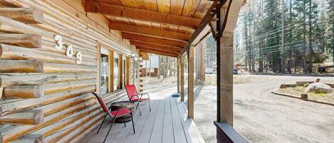 Eine Blockhütte mit Veranda, Zimmer Nummer 309 und Blick auf den umliegenden Wald.