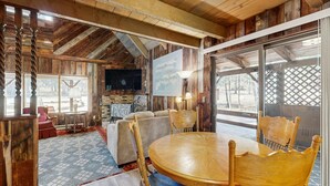 Un interior rústico con chimenea, muebles de madera y un gran ventanal.