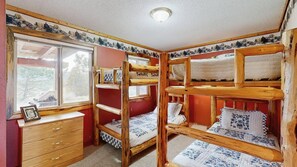 Habitación con literas, un armario de madera y una lámpara en el techo.