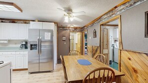 A compact kitchen with a refrigerator, coffee maker, and wooden dining table with chairs.