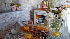 Une table à manger recouverte d’une nappe à motifs floraux, entourée de différents plats, de verres et de condiments.