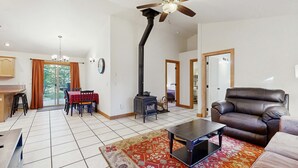Una sala de estar con sofá, mesa de centro, chimenea, ventilador de techo y comedor con mesa y sillas.