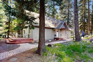 A cabin with a porch, a small deck, and a satellite dish.