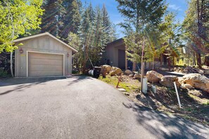 A garage with a number 1290, a driveway, and a house surrounded by trees and rocks.