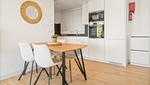 Eine moderne Küche mit weißen Schränken, einem eingebauten Ofen und einem Essbereich mit Holztisch und Stühlen.