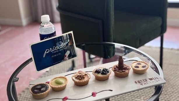 A glass table with a selection of pastries, a bottle of water, and a sign with the name 'Priedo' in a hotel setting. - PRIEDE HOTEL BOUTIQUE (Puebla)