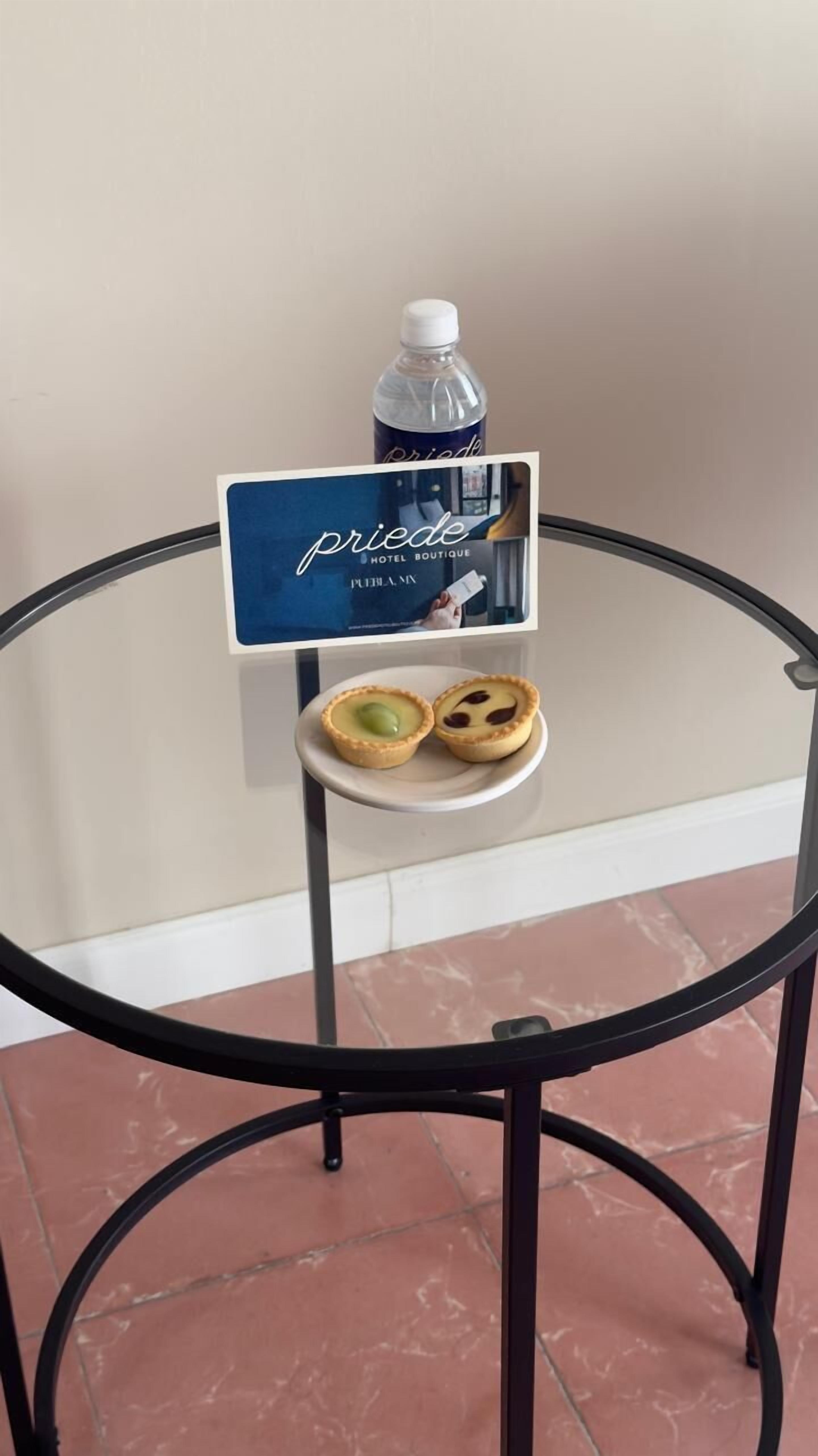 A glass table with a sign for 'pride hotel boutique,' a bottle of water, and two small pastries.