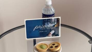 A glass table with a sign for 'pride hotel boutique,' a bottle of water, and two small pastries.