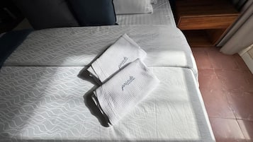 Una cama bien tendida con ropa de cama estampada y dos toallas dobladas con la palabra 'poderosa' en ellas.