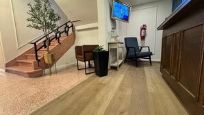 A lobby with a staircase, a flat-screen TV, a fire extinguisher, and a wooden cabinet. - PRIEDE HOTEL BOUTIQUE (Puebla)