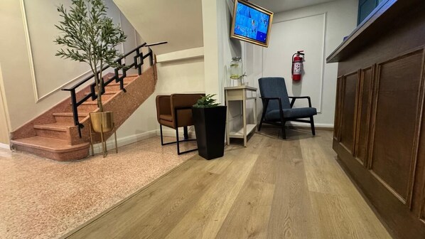 Un hall d’entrée avec un escalier, un téléviseur à écran plat, un extincteur et un meuble en bois.