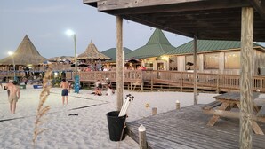 A beachside wooden deck with a thatched-roof building in the background. - Sand Dollar 6mi-Pensacola Bch (Gulf Breeze)